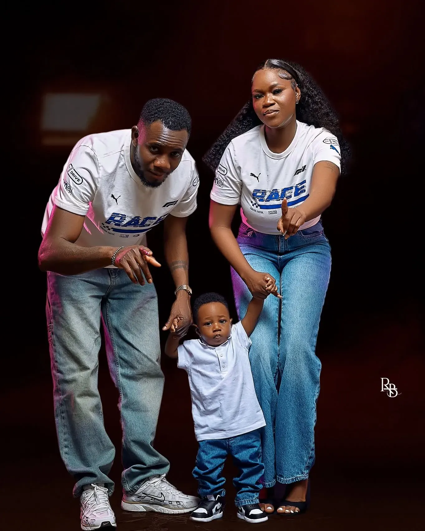 Two adults and a child stand together wearing coordinated white shirts.